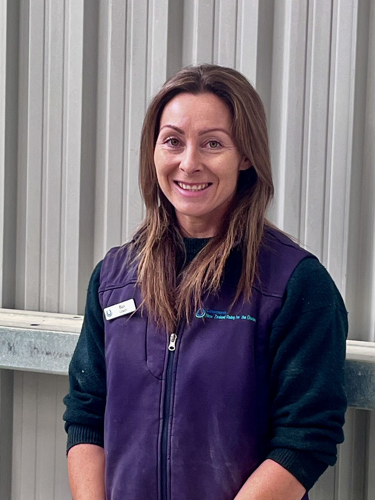 A smiling woman with long brown hair in a purple fleece