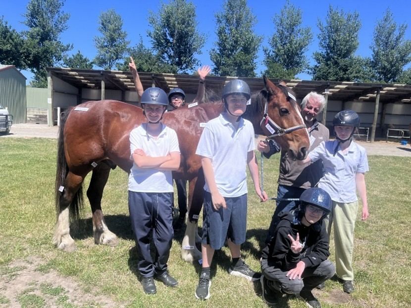 A school group standing with Copper outside the stables