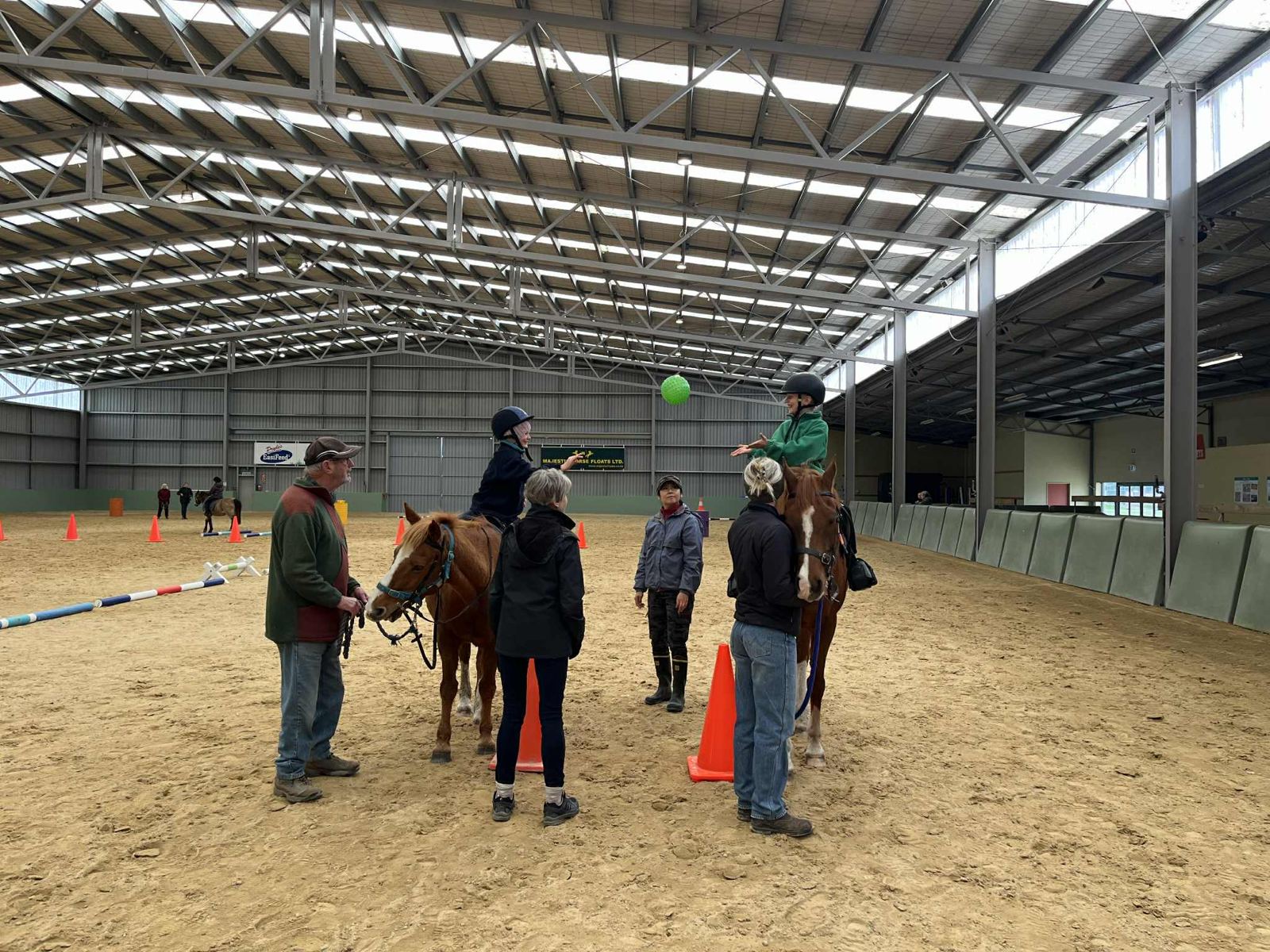 A coach and volunteers guiding a rider through cones in the arena