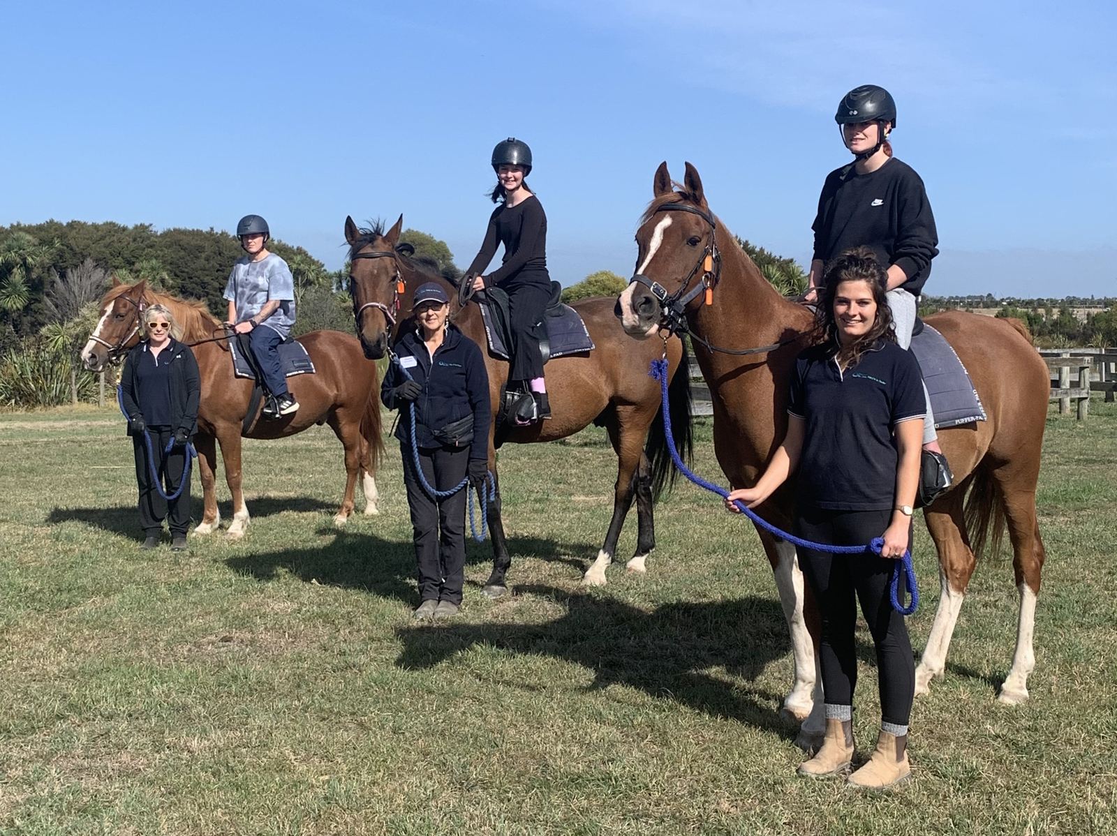 Sport and recreation riders on horseback with their coach on a sunny field
